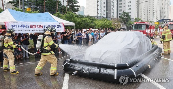 전기차 화재 진압 시연(인천=연합뉴스) 임순석 기자 = 13일 오전 인천 연수구 송도 2동 행정복지센터 주차장에서 열린 전기자동차 화재대응 민·관 합동 교육에서 소방관들이 질식소화포와 전기차 수조탱크를 이용한 전기차 화재 진압 모의 시연을 하고 있다. 2024.8.13